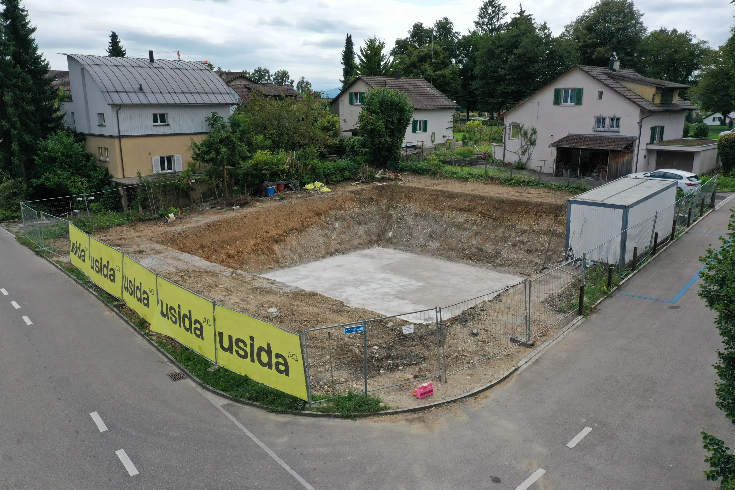 Baugrube in Bassersdorf mit Bauzaun und Usida-Bannern