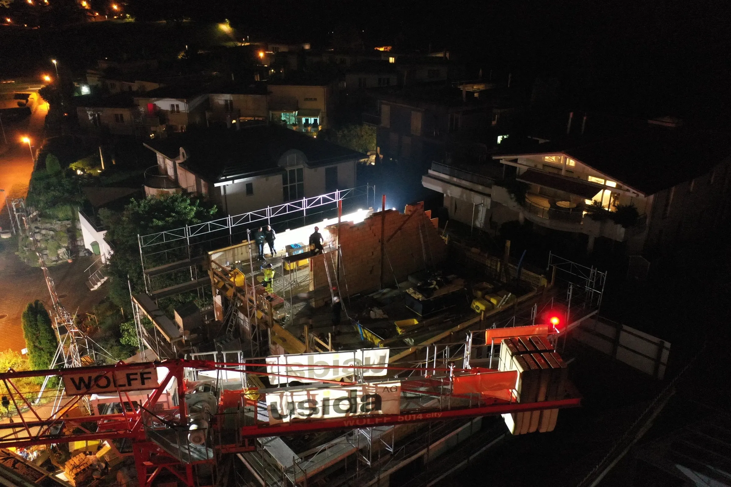 Baustelle mit beleuchtetem Kran bei Nacht