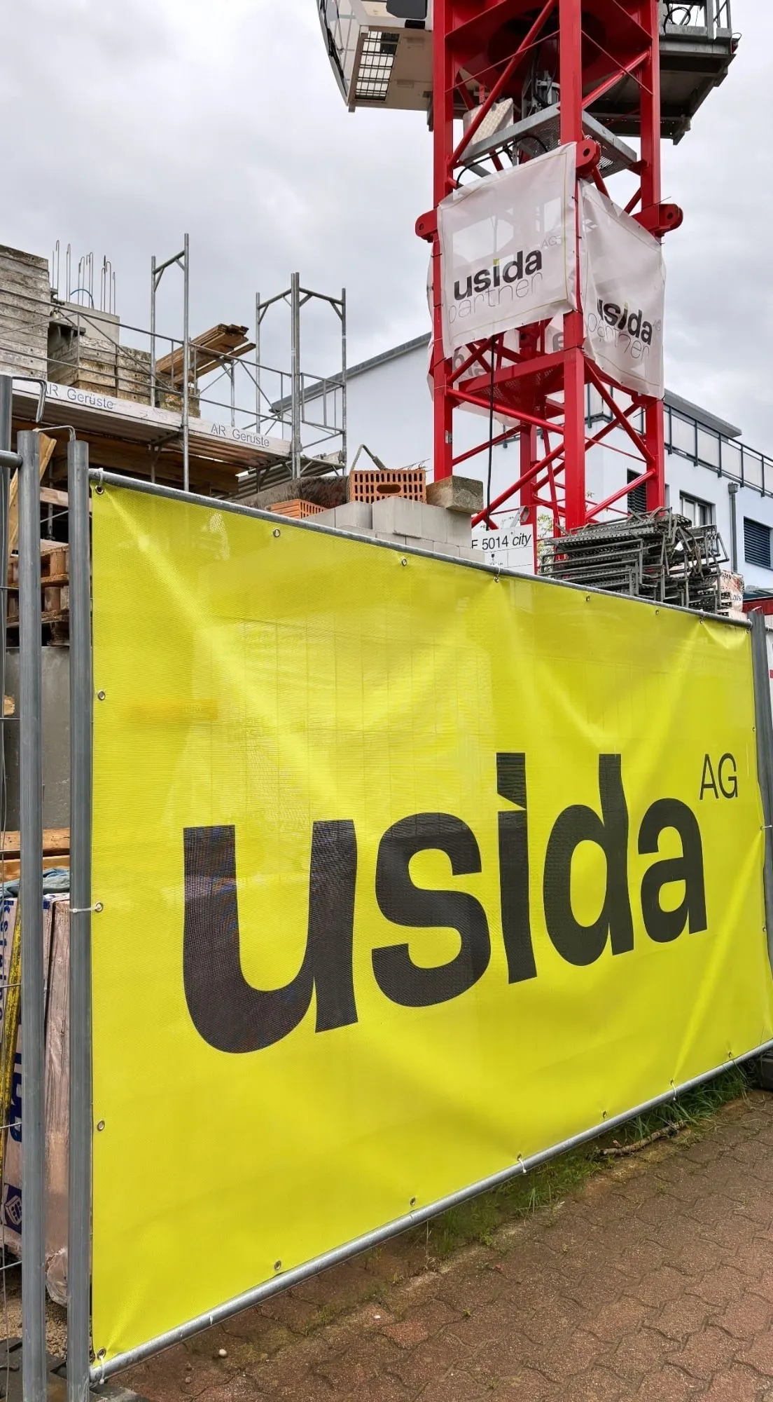 Baustelle mit Usida-Banner am Bauzaun und am Kran